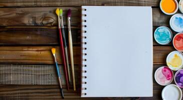 Blank Sketchbook and Paints On Wooden Table in Natural Light photo