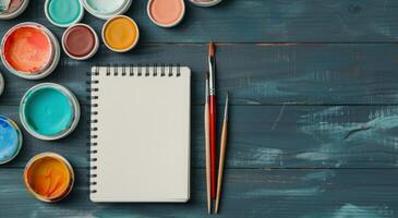 Blank Sketchbook and Paints On Wooden Table in Natural Light photo