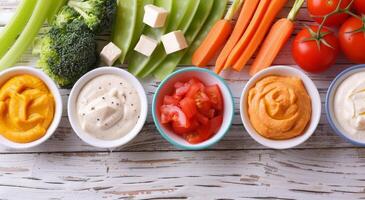 Fresh Vegetables and Dipping Sauce Displayed on Rustic Wooden Table photo