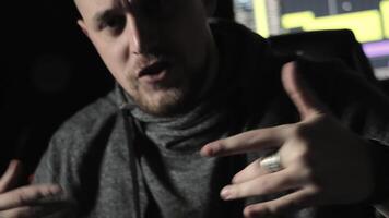 Close-up of a person expressing emotions with hand gestures, A close-up image of a person in a dimly lit room, using expressive hand gestures while speaking. video