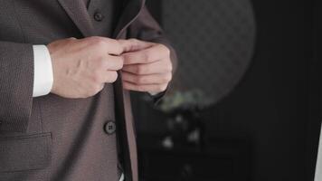 Groom adjusting his suit jacket before the wedding, A close-up image of a groom's hands adjusting the button on his suit jacket. video