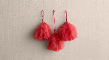 Red Decorative Tassels Hanging on a Branch Against a Rustic White Background photo