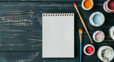 Blank Sketchbook and Paints On Wooden Table in Natural Light photo