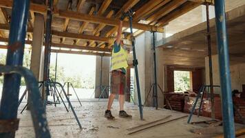 Construction Worker Adjusting Support Beams on Site. A construction worker in a reflective vest adjusts the support beams at a building site. video