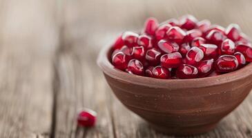 Fresh Pomegranate Seeds in a Bowl on Wooden Table photo