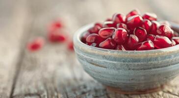 Fresh Pomegranate Seeds in a Bowl on Wooden Table photo