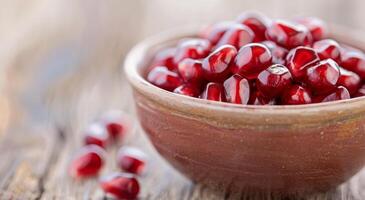Fresh Pomegranate Seeds in a Bowl on Wooden Table photo