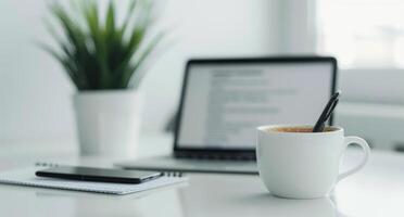Modern Workspace With Laptop, Mug, and Potted Plant on White Desk photo