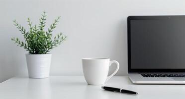 Modern Workspace With Laptop, Mug, and Potted Plant on White Desk photo