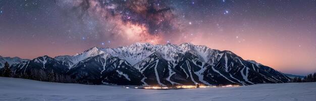 Snow-Covered Mountains at Dusk With Light Glowing in the Valley photo