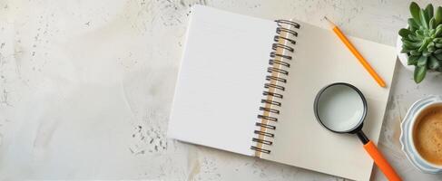 Open Notebook With Magnifying Glass, Orange Pen, Coffee, And Succulent Plant On Table photo