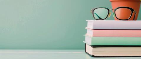 Pink Glasses Resting on Stacked Notebooks With Succulents in Background photo