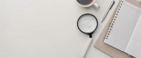 Magnifying Glass on Notepad With Pen and Succulent Plant on White Surface photo