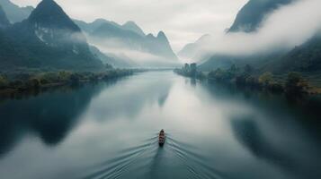 Rowboat Gliding Across Calm River at Dawn Near Misty Mountains photo