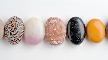 Colorful Variety of Polished Stones Displayed in a Row on a White Surface photo