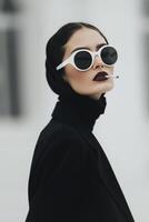Elegant Woman in Black Attire Smoking With Stylish Sunglasses Outdoors photo