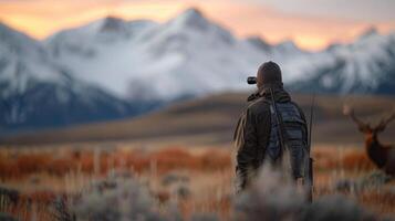 Hunter Observing Wildlife at Dusk in Mountainous Landscape photo