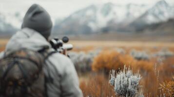 Hunter Observing Wildlife at Dusk in Mountainous Landscape photo