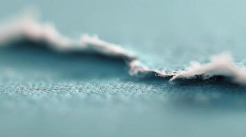 Close-Up View of Frayed Fabric Edge on Soft Blue Material photo