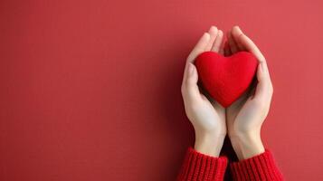 Hands Cradling a Red Heart Against a Solid Red Background photo