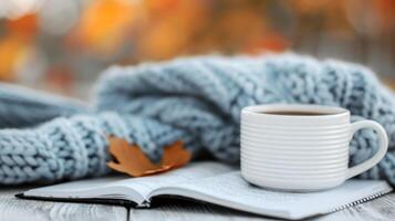 Cozy Autumn Moment With Hot Beverage, Knitted Blanket, and Leaves on a Table photo
