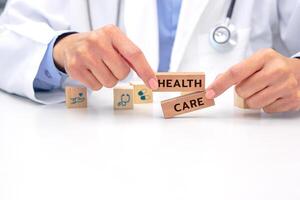 Hand of doctor holding a wooden block cube with text and behind it is a wooden block with blurred icon symbol. Medical and health concept. photo