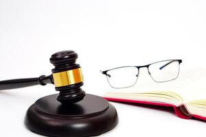 Close up of judge gavel or hammer and blurred glasses on the law book placed behind. Law, judiciary concept. photo