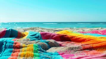 Brightly colored beach towel on a sandy beach with clear blue ocean and sky in the background, capturing a vibrant summer scene photo