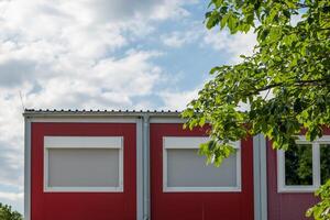 red building with a white roof and two windows photo