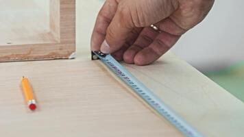 Close-up shot of a man's hands, those of a true labourer, engaged in the task of measuring distance using a measuring tape. Close up. Slow motion video