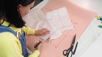 Seamstress carefully cuts an extra piece of paper from her patterns, along the dotted line. Top view video