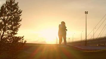 Silhouette of two lovers, embracing in the setting sun, against the backdrop of the city skyline. Slow motion video