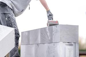 the mason applies glue to the concrete forms. construction of a wall of concrete bricks photo