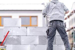 a mason builds the wall of a building from concrete bricks and blocks photo