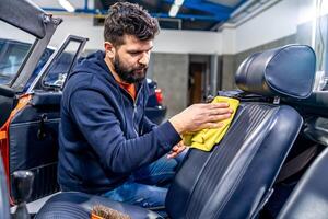 manual cleaning of the leather in the interior of the car with a micro towel photo