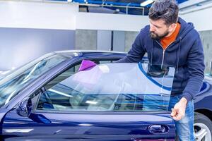 manual cleaning of luxury car windows with a microfiber towel in the garage photo