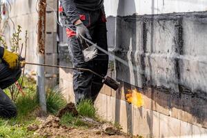 installation of protective waterproofing on the foundation and walls of the building. warmed by an open fire photo