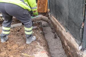 pour concrete from the mixer of the foundation of the building in the ground photo