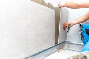 installation of large format tiles on the wall by a craftsman photo