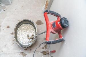 manual mixing of cement with the help of an electric mixer, cement in a bucket on a construction site photo