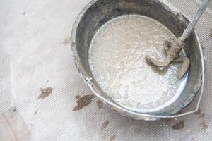 manual mixing of cement with the help of an electric mixer, cement in a bucket on a construction site photo