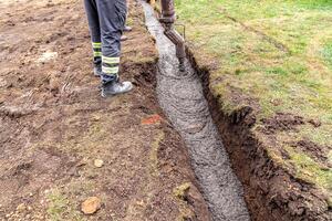 pour concrete from the mixer of the foundation of the building in the ground photo