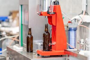 capping beer bottles on a machine in a brewery photo