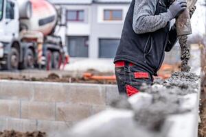 pouring concrete from a mixer truck with a hose into the foundation of the house photo