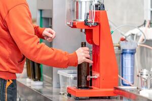 capping beer bottles on a machine in a brewery photo