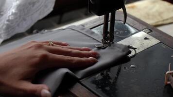 Hands deftly operate the mechanisms of a vintage sewing machine, showcasing the skilled craft of garment making and the timeless appeal of handmade textiles video