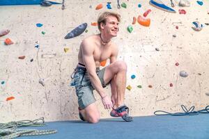 putting on climbing shoes next to the climbing wall photo
