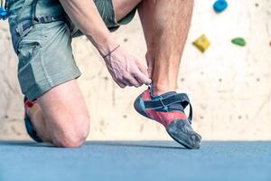 putting on climbing shoes next to the climbing wall photo