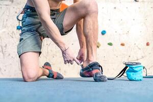 putting on climbing shoes next to the climbing wall photo