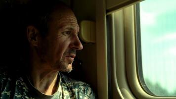 Close-up of a man looking out the window in a train compartment video